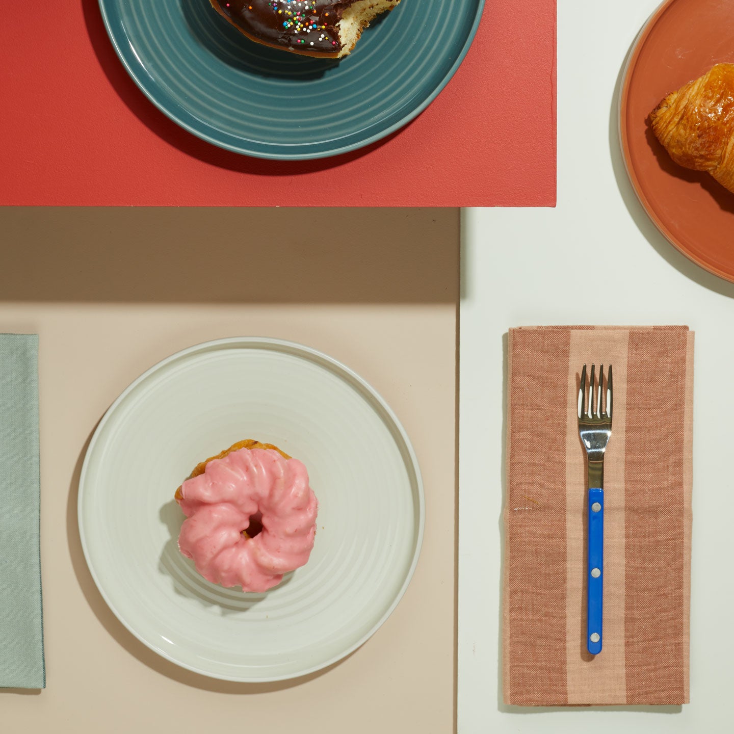 Essential Plates with donuts and Essential Striped Blush Dinner Napkin with blue fork.