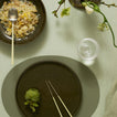 Dinner setting with a plate of food, a glass, and a flower arrangement on a light green table.