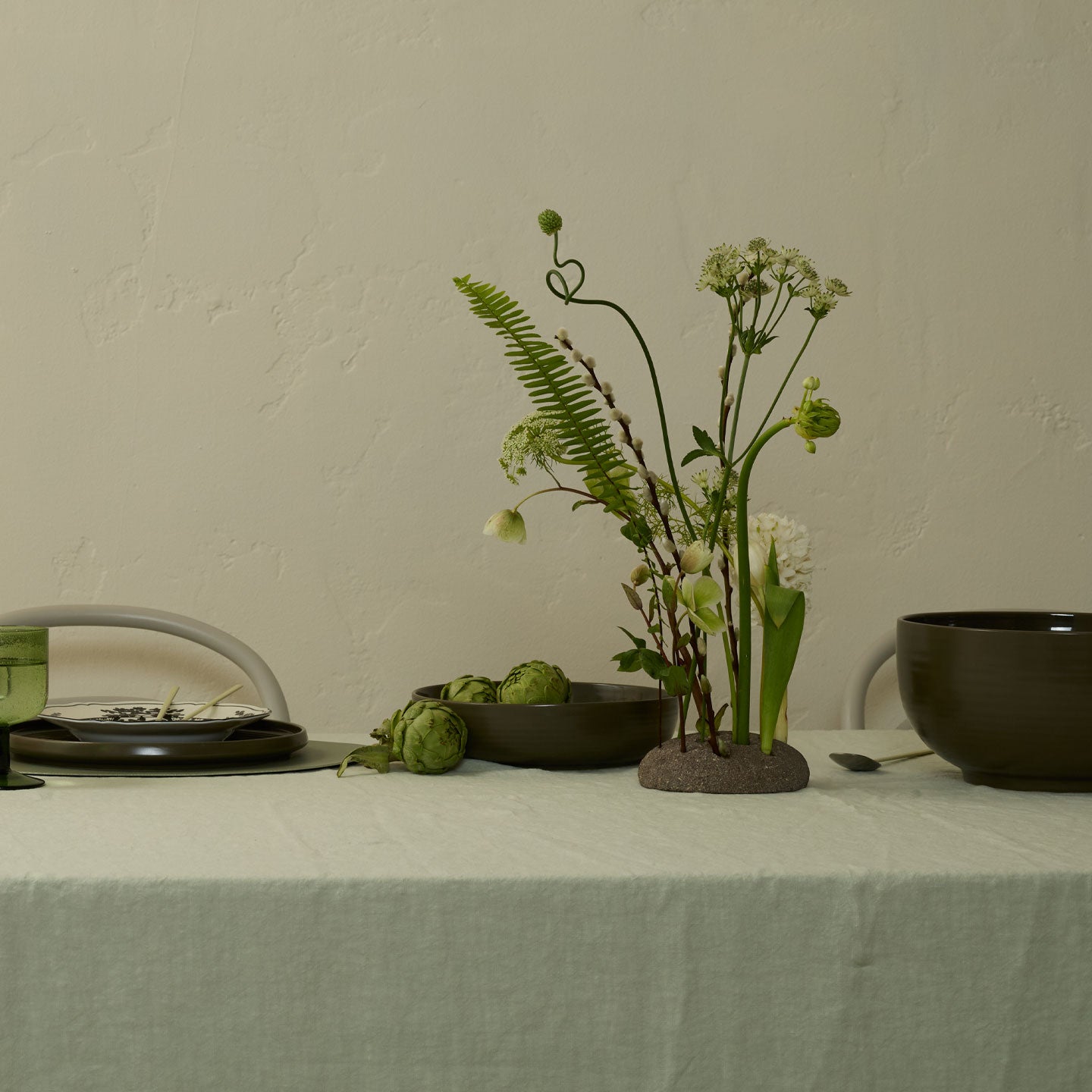 Decorative arrangement of plants and bowls on a table with a neutral background