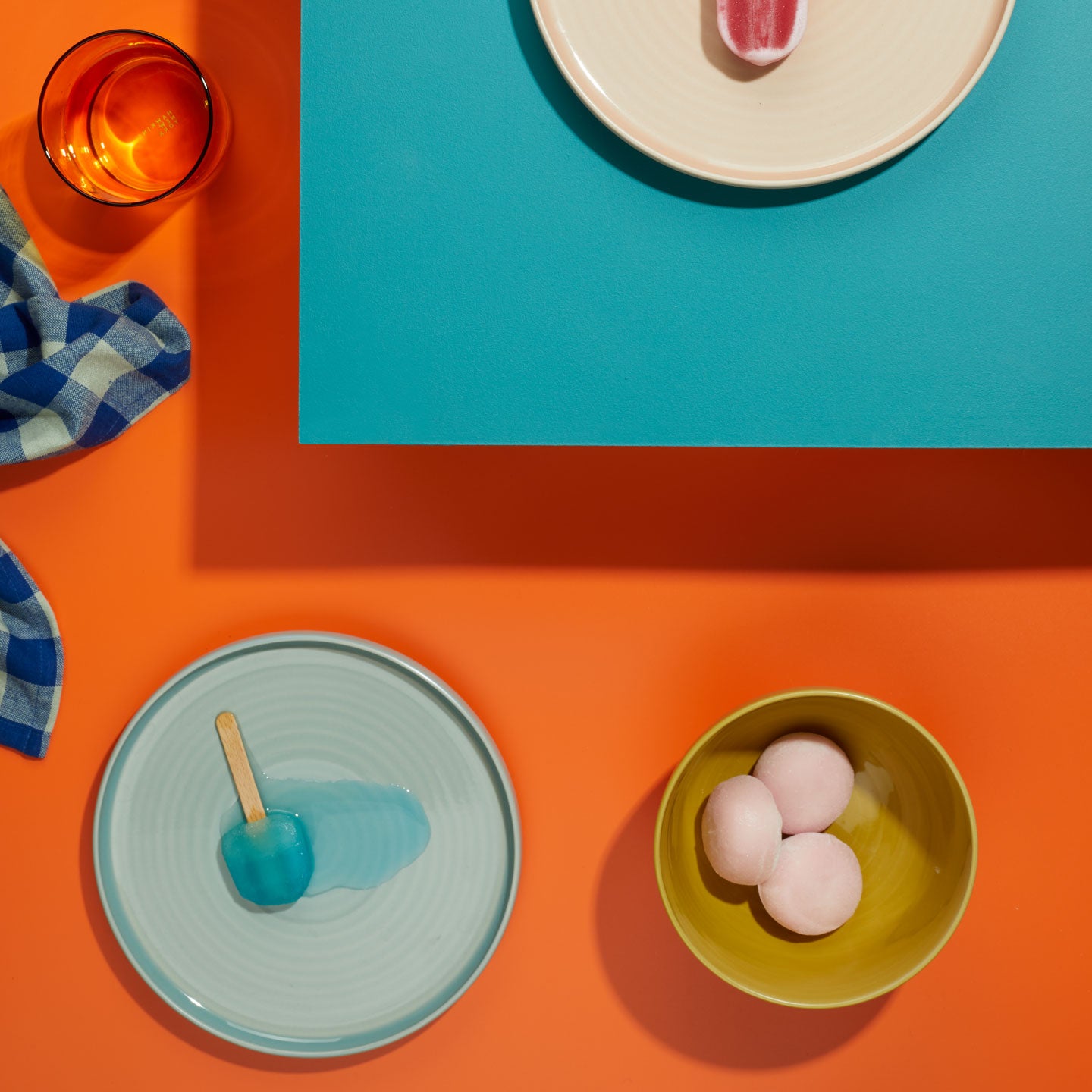 Colorful table setting with plates, bowls, and a glass on a multicolored background