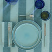 Placesetting with Essential Dinner Plate in Sky on blue striped tablecloth.