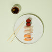 Sushi plate with sushi, wasabi, and soy sauce on a light green background