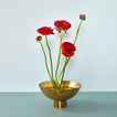 Brass footed bowl with red flowers on blue background.