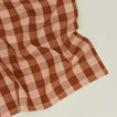 Close up view of Essential Gingham napkin in blush/terracotta