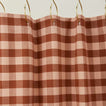 Gingham shower curtain in blush/terracotta on gold curtain hooks