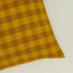 Close up view of gingham square pillow in mustard/bronze