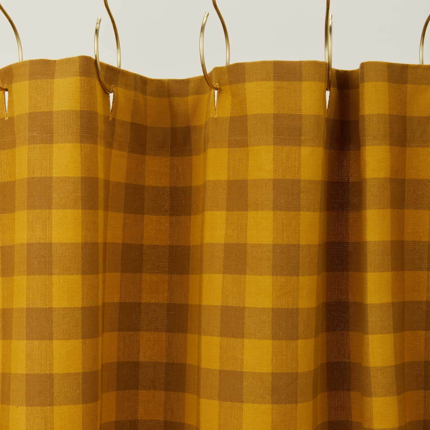 Gingham shower curtain in mustard/bronze on gold curtain hooks