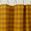 Gingham shower curtain in mustard/bronze on gold curtain hooks