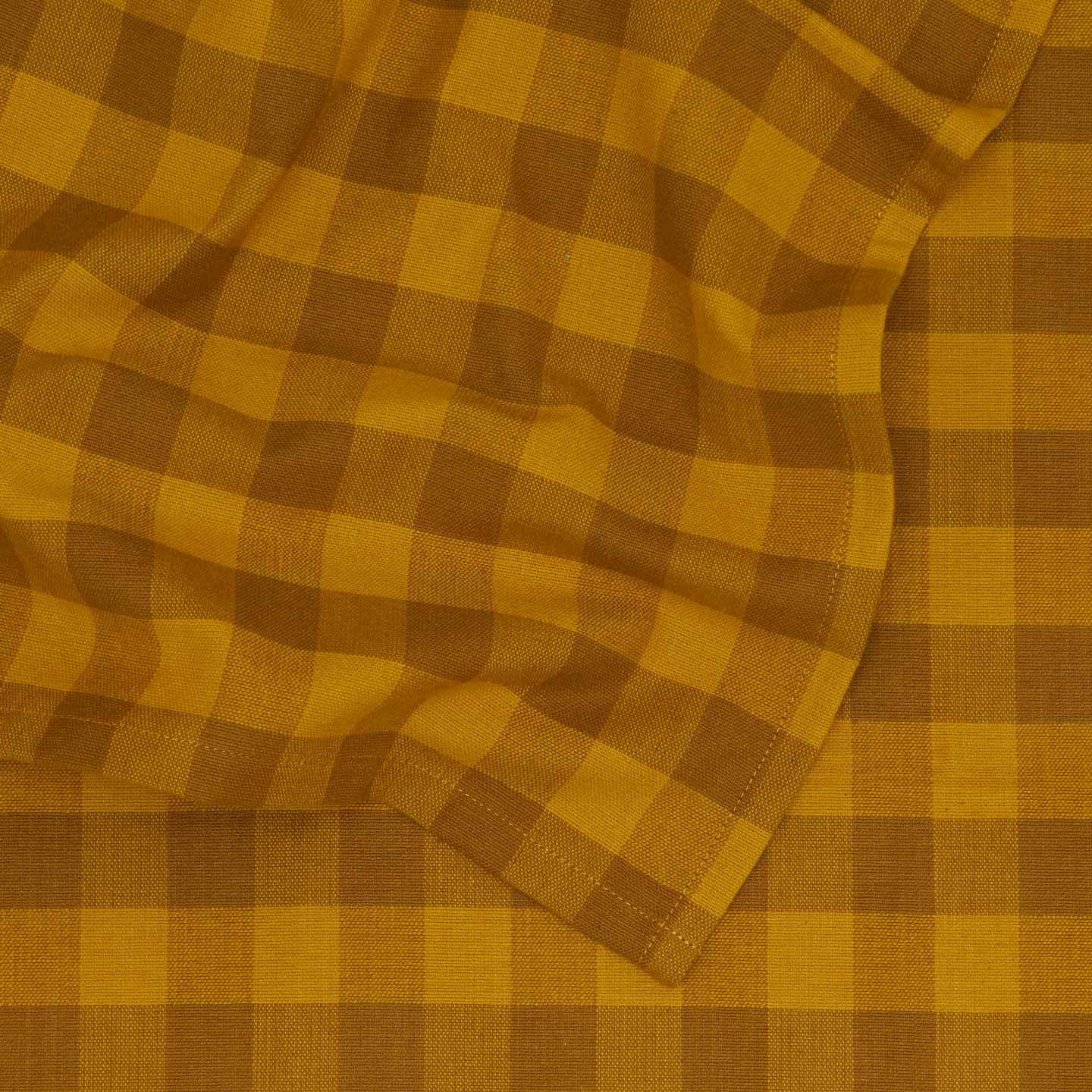 Close up view of Essential Gingham tablecloth in mustard/bronze