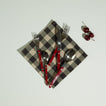 Essential Gingham Napkin in Black and Grey on light surface with red flatware and cherries on the side.