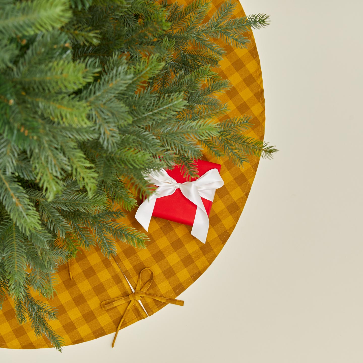 Overhead view of Essential GIngham Tree Skirt - Mustard/Bronze with tree