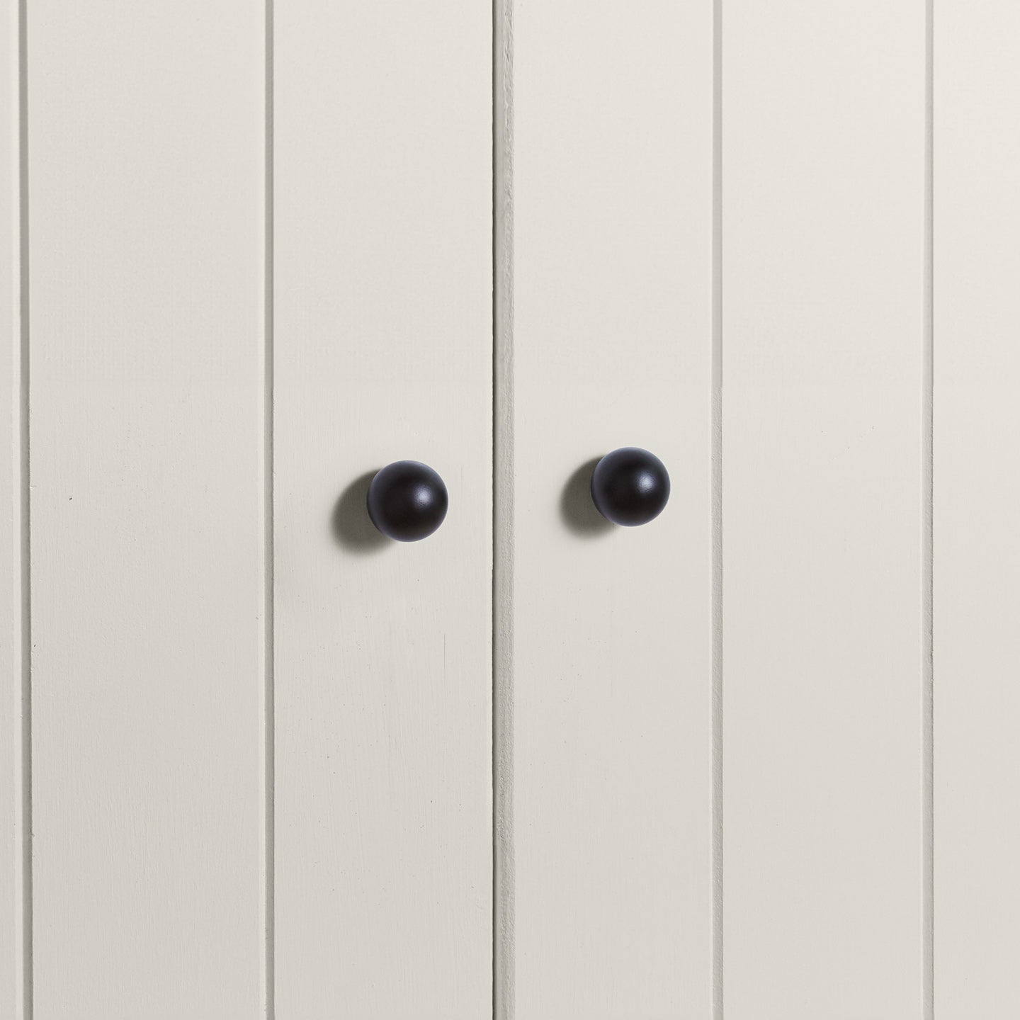 Small black essential sphere knobs on white doors