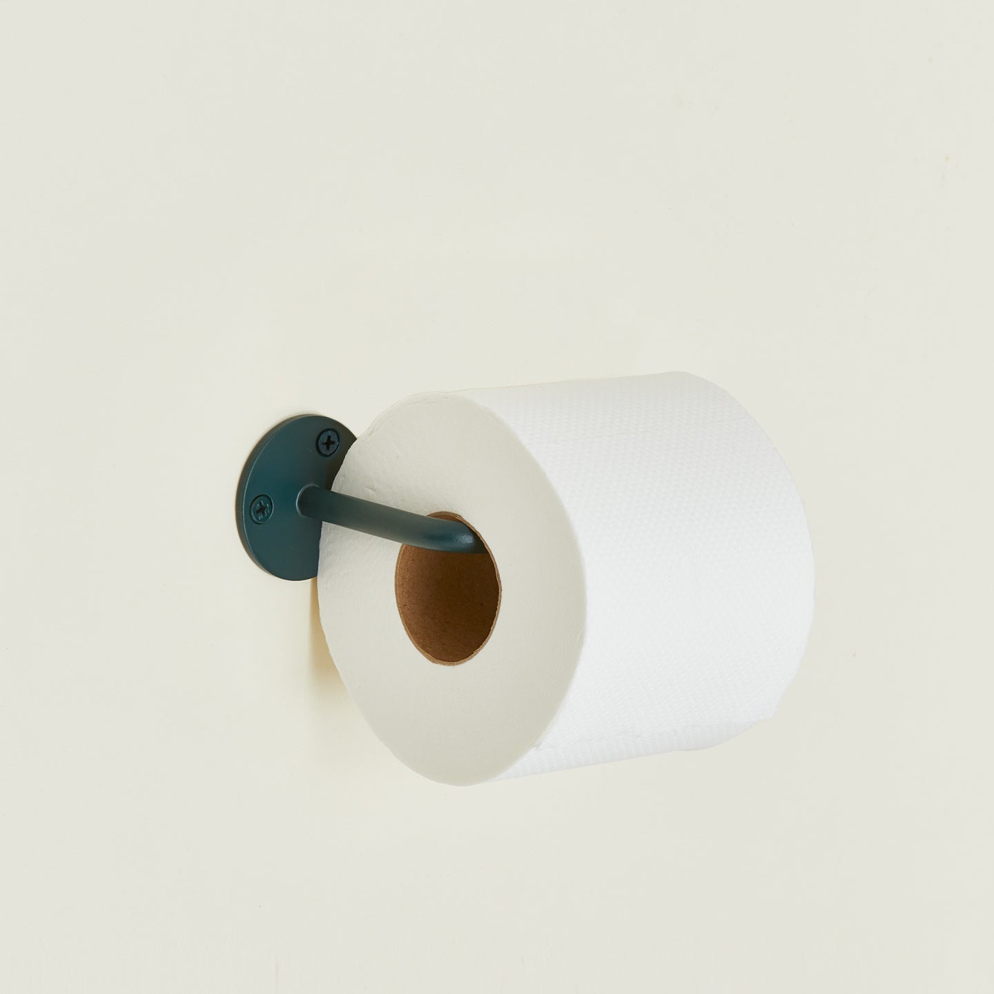 Toilet paper holder in Dark Peacock with a roll of toilet paper.