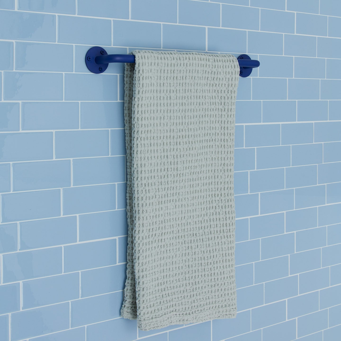 Essential towel bar in klein blue on a tile background.