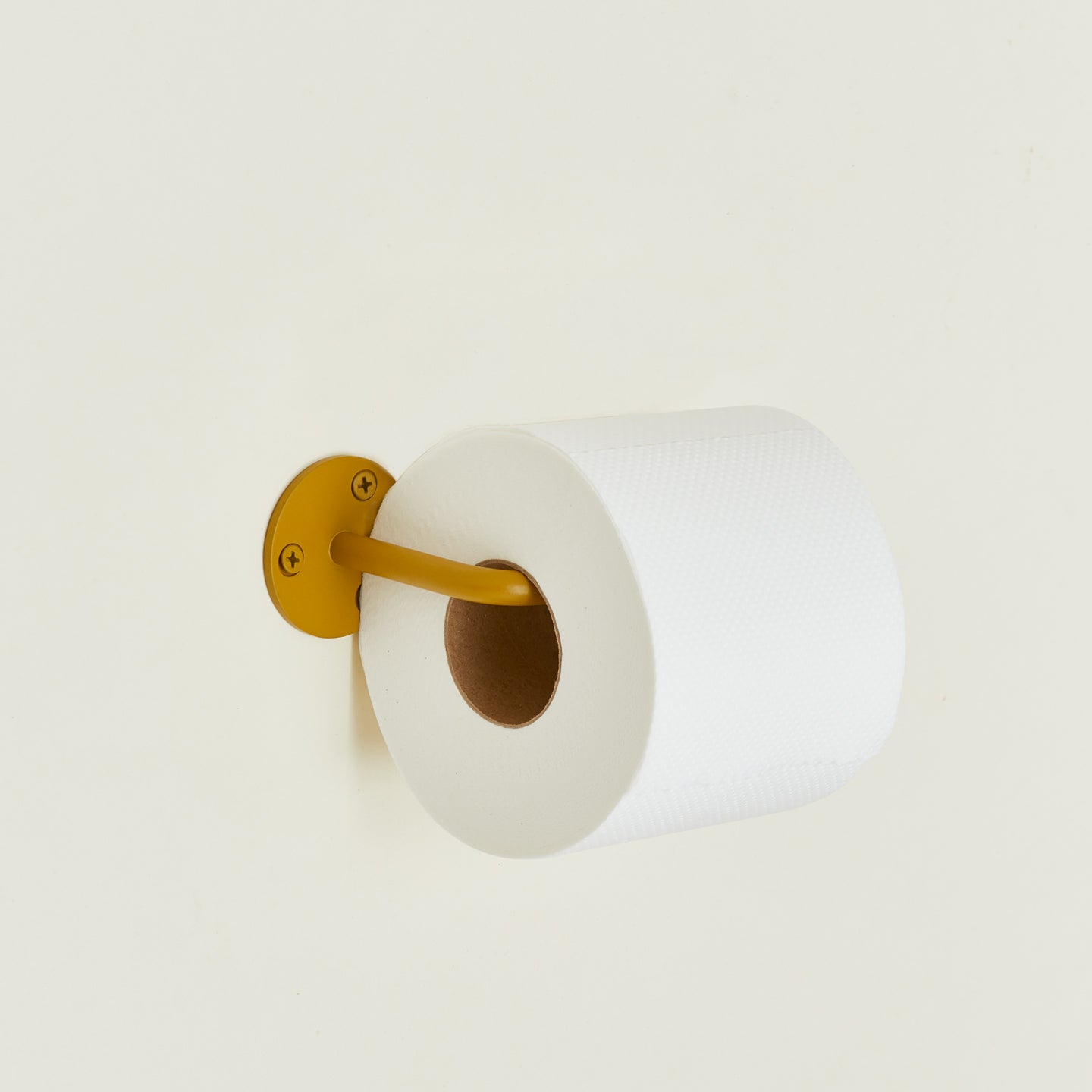 Toilet paper holder in Mustard with a roll of toilet paper.