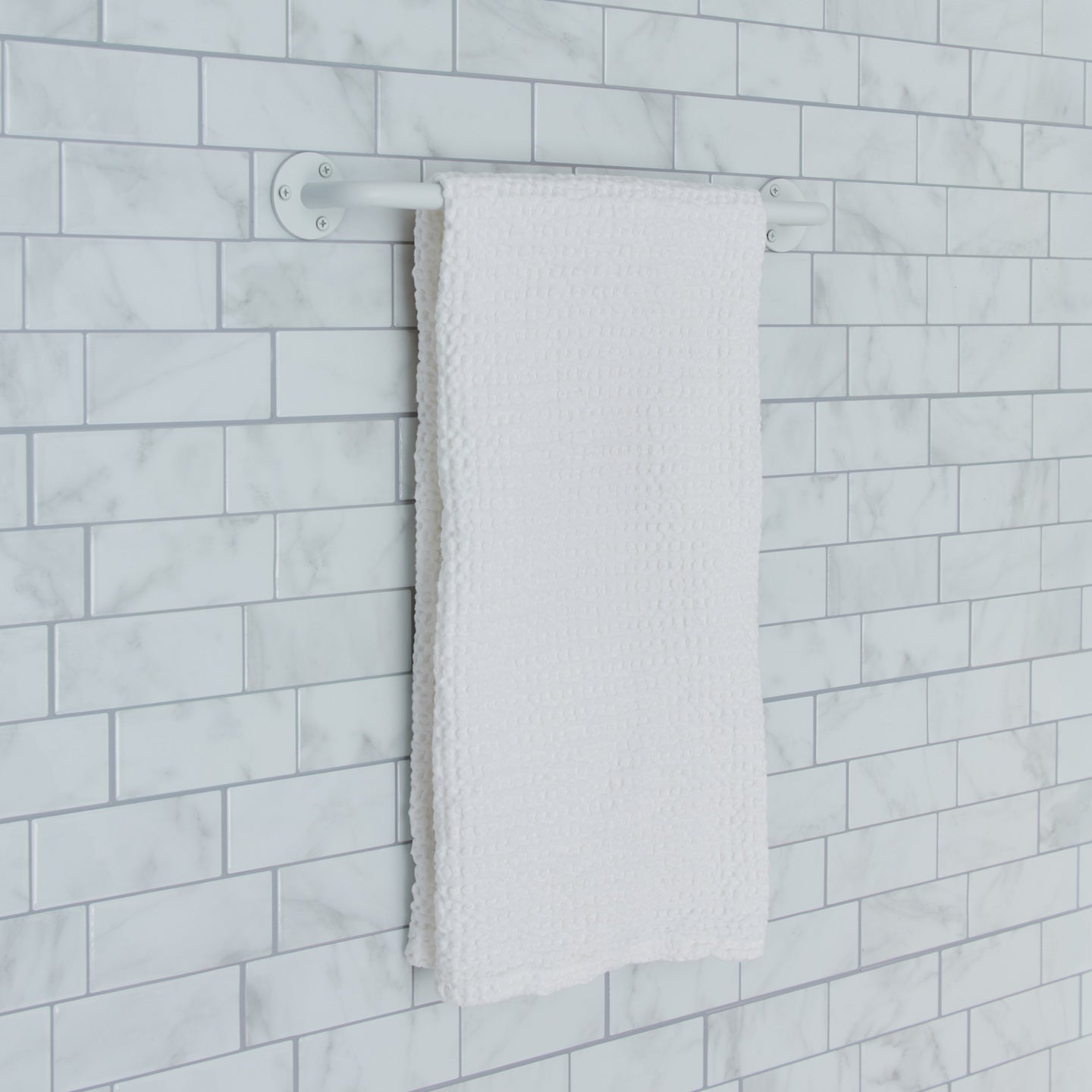 Essential towel bar in white on a tile background.