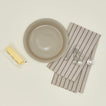 Essential pie dish in light grey with measuring spoons, butter, and dish towel