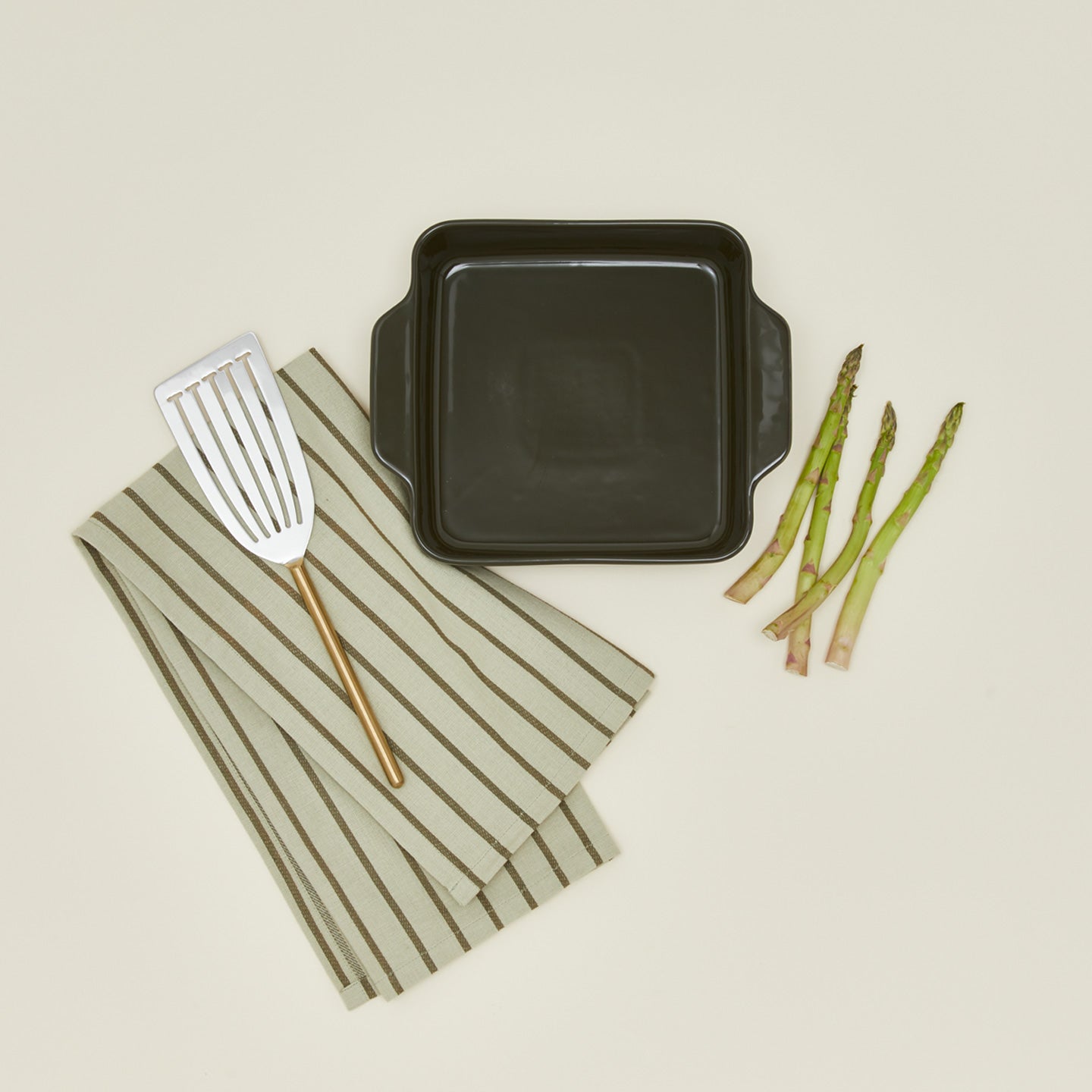 8" x 8" Essential bakeware in olive with asparagus, fish spatula, and dish towel