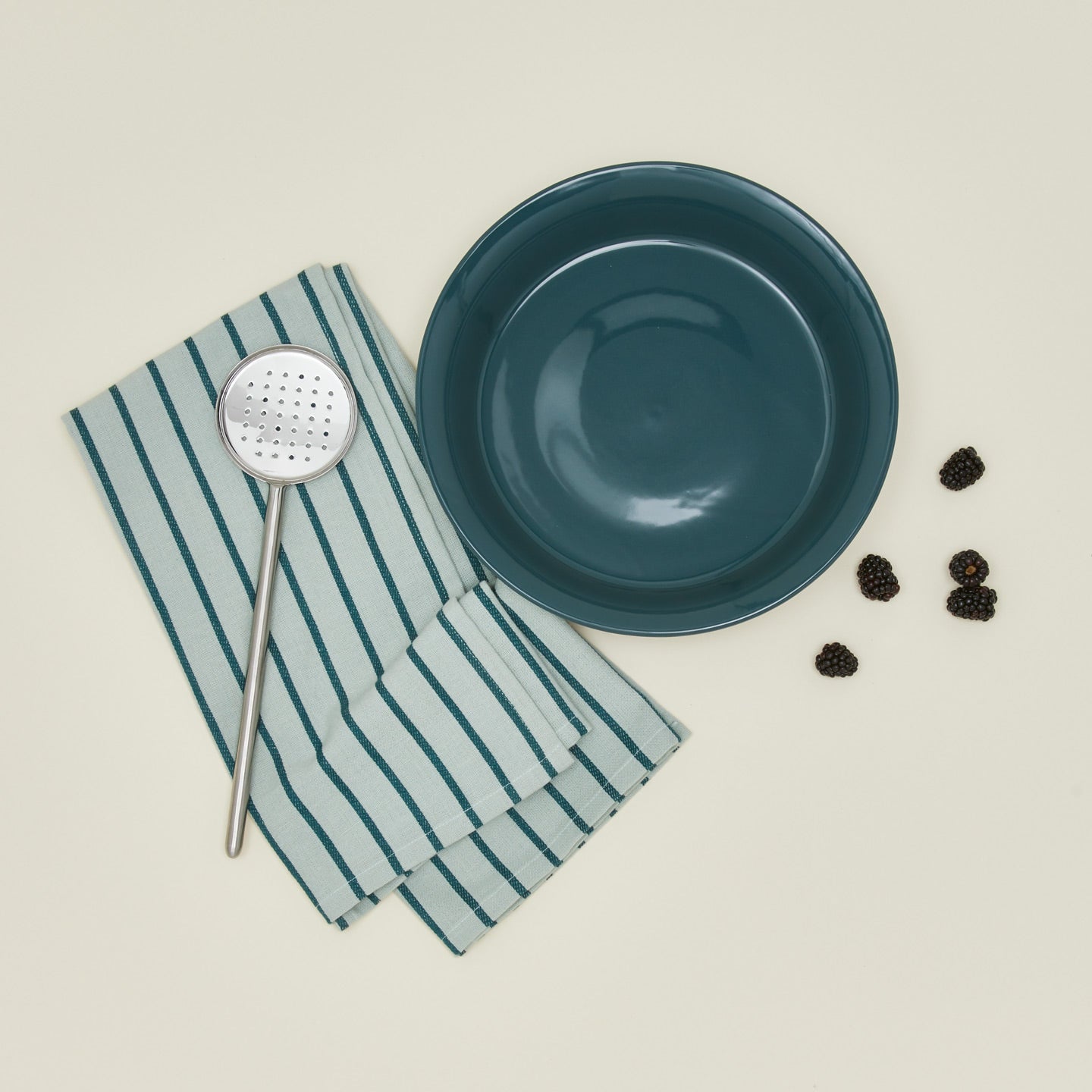 Pie dish with blackberries dishtowel and slotted spoon