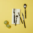 Essential Striped Napkin in Ivory with black flatware and kiwi on yellow background.