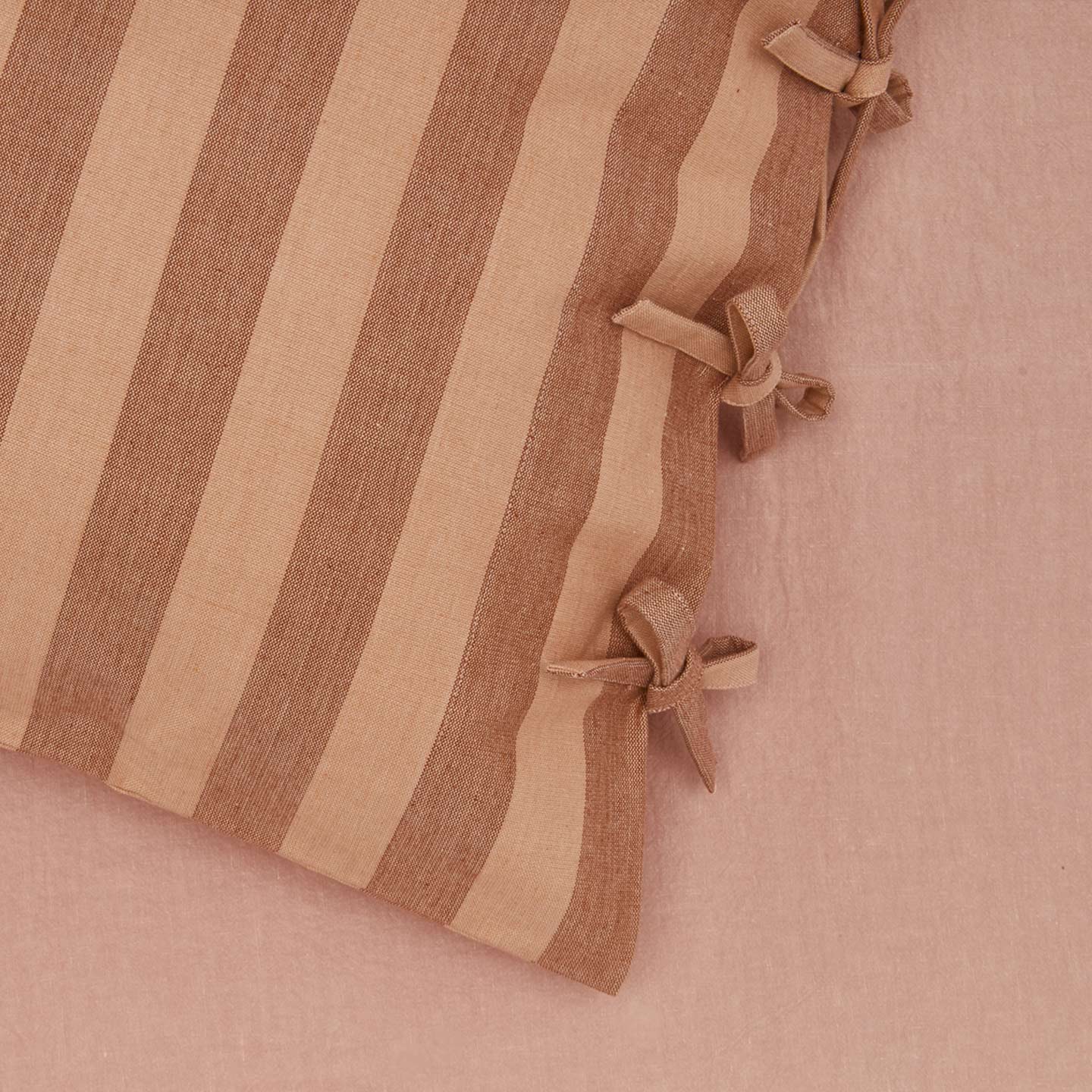 Close up view of essential striped pillowcase in blush/terracotta