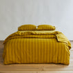 Essential Stripe Pillowcases, Set of 2 - Mustard/Bronze on bed with matching duvet