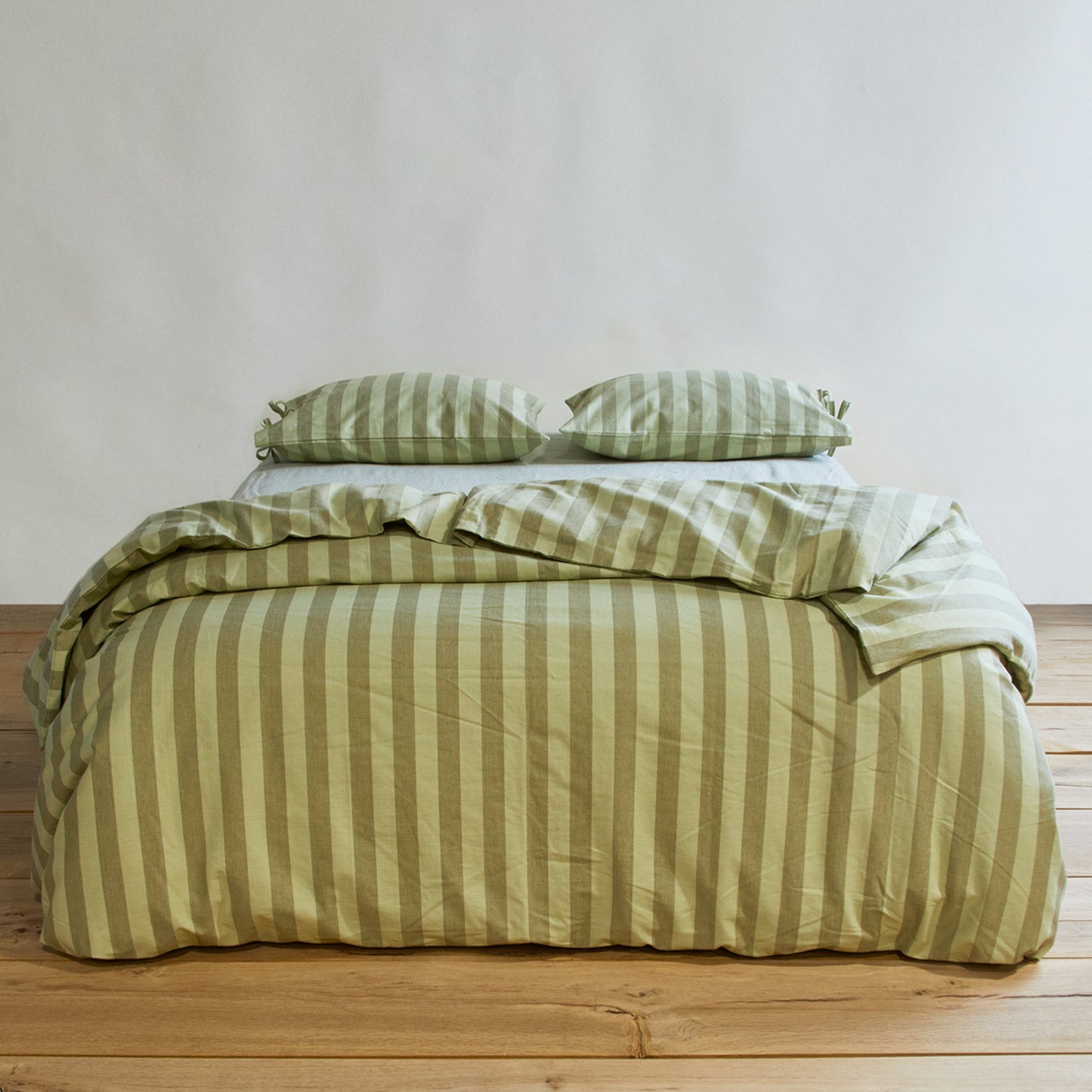 Essential Stripe Pillowcases, Set of 2 - Sage/Olive on bed with matching duvet.