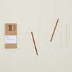 Kraft colored gift box of Essential Glass Straws in Warms, with straws scattered nearby.