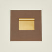 Brass dough scraper on a brown paper on a beige background.