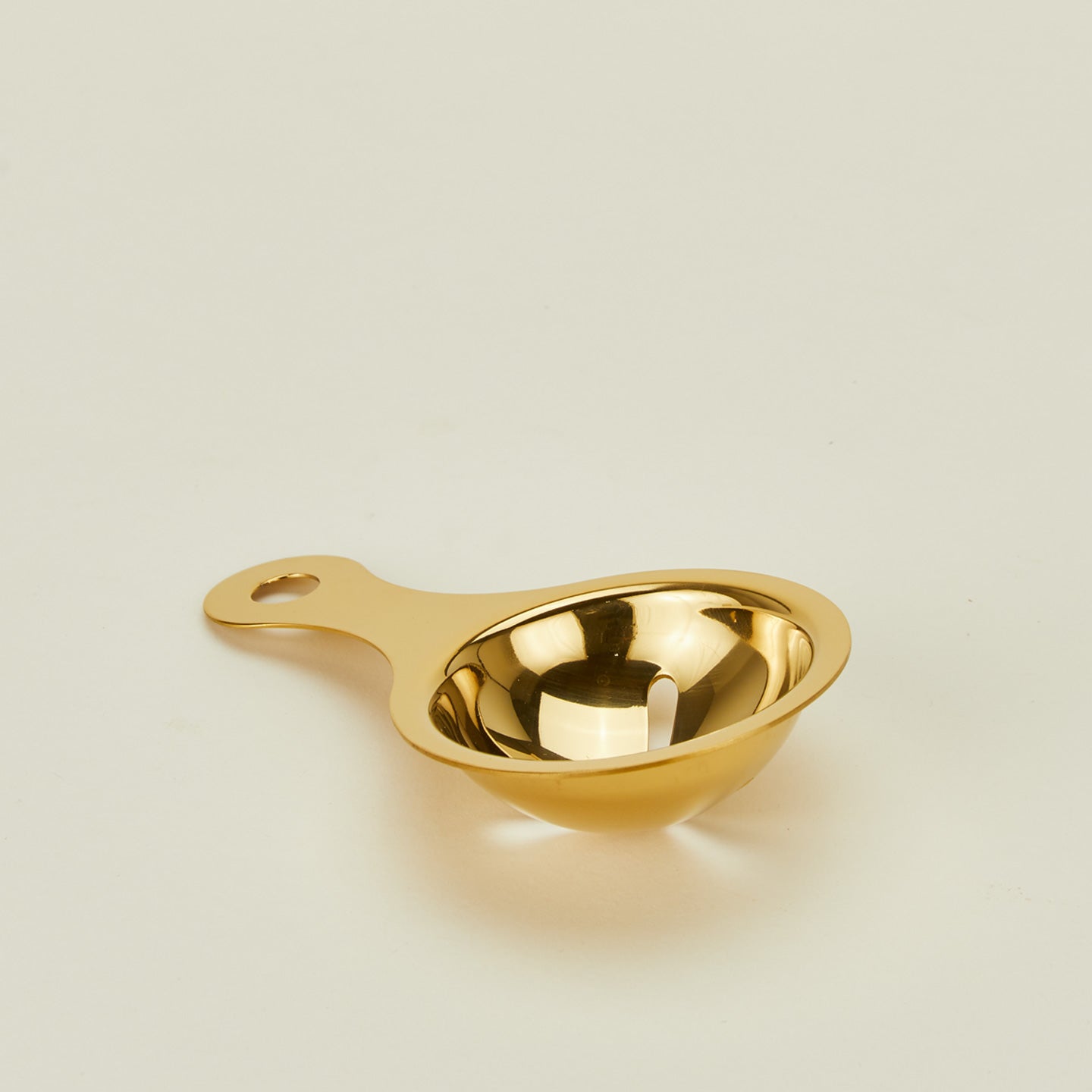 Close up of brass egg separator on a beige background