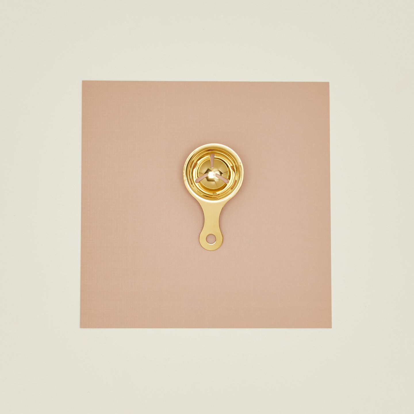 Brass egg separator on a beige background