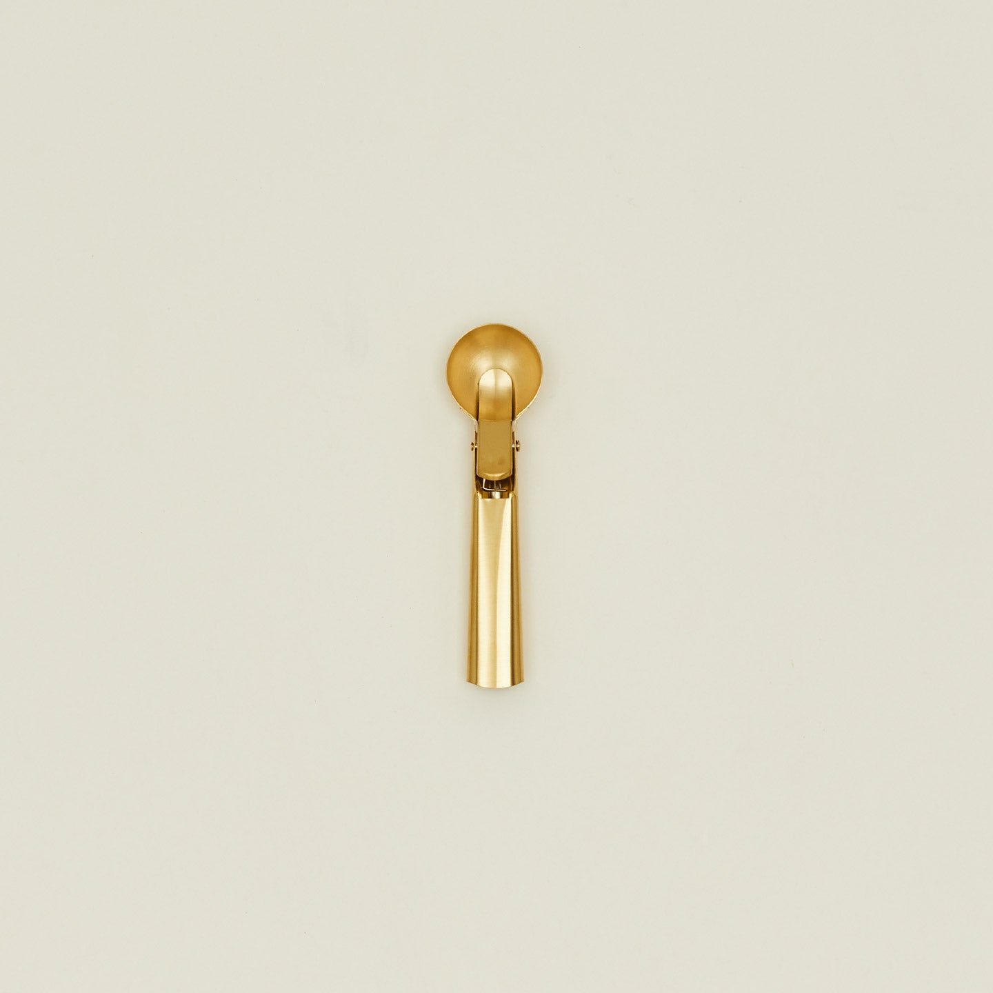 Brass ice cream scoop on a beige background