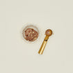 Chocolate ice cream in a small bowl with a brass spoon on a beige background