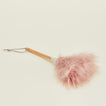 Close up of Pink feather duster with wooden handle on a beige background