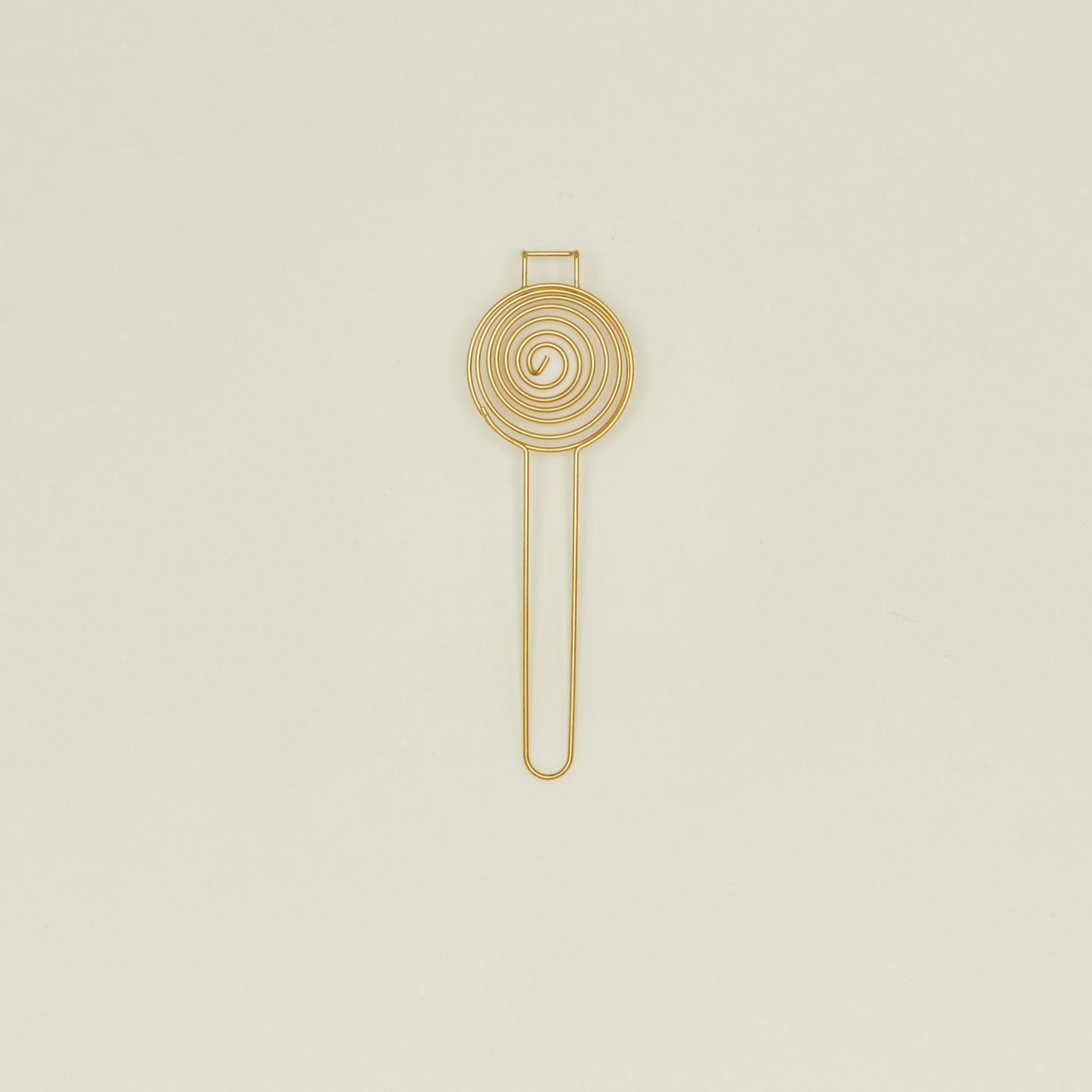 Brass swirl egg separator on ivory background.