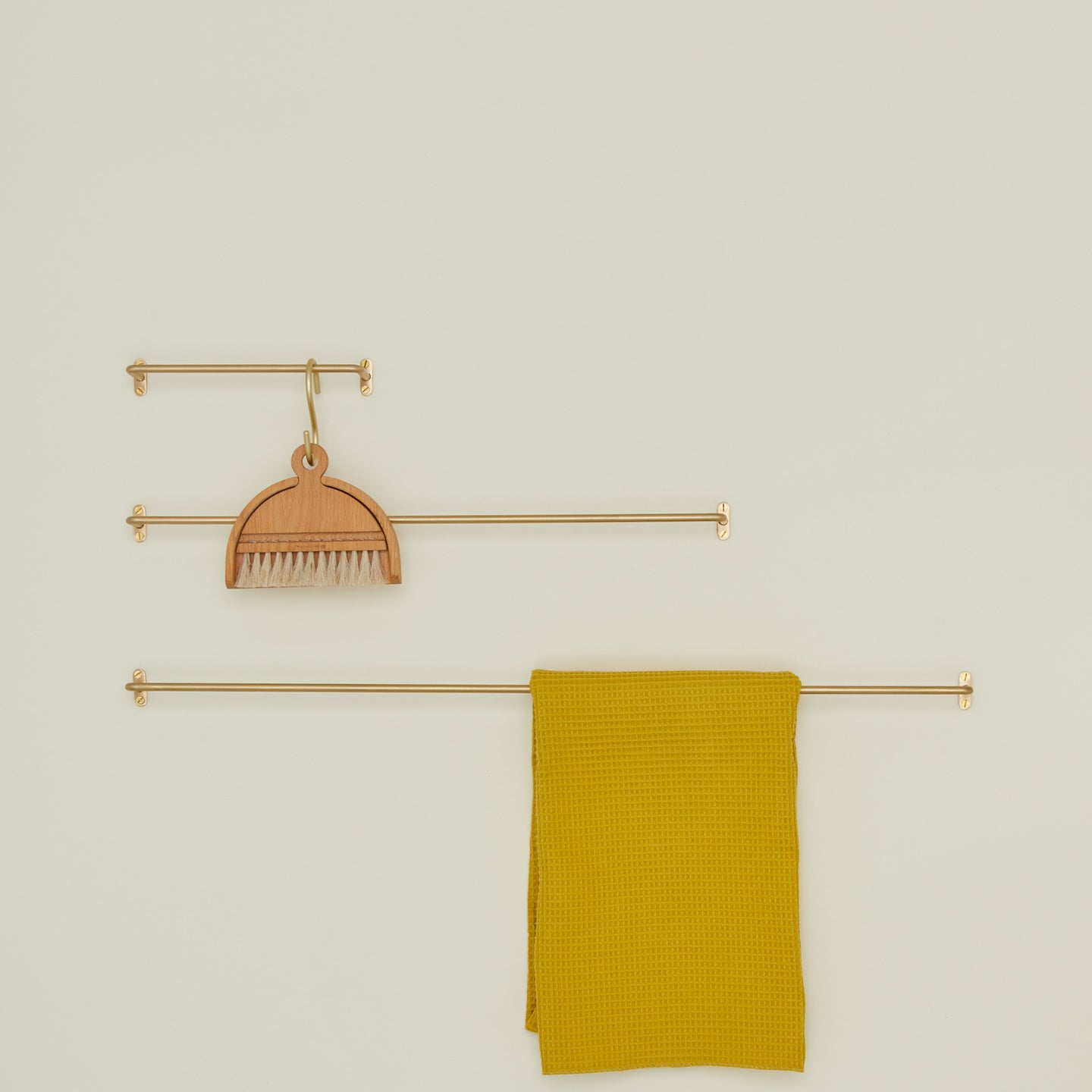 Brass towel bar family in various sizes with small broom and dustpan and mustard waffle towel