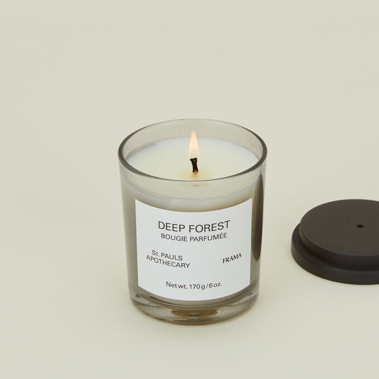 A close up of a lit wax candle with the scent Deep Forest.