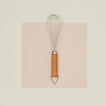 Stainless steel whisk with wooden handle on paper.