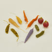 Colorful vegetable candles including carrots, peas, and radishes on a light background