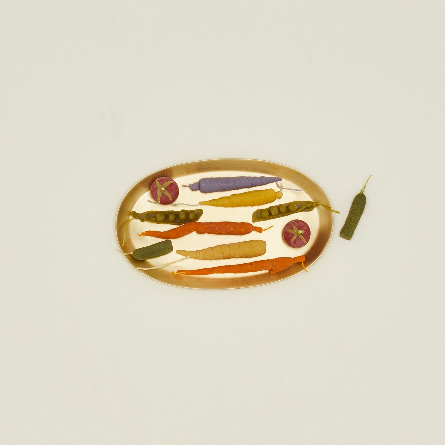 Decorative plate with colorful vegetable candles on a beige background