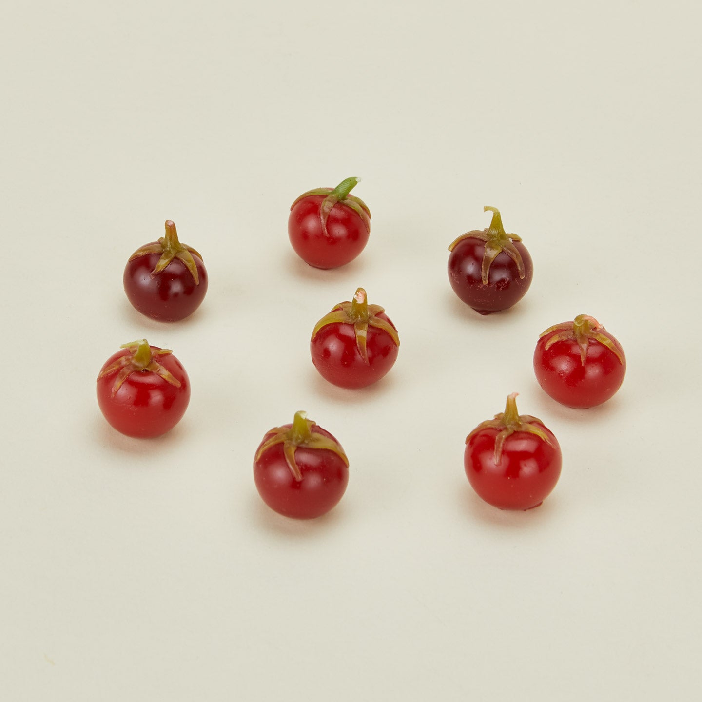 Red tomato candles on a beige background