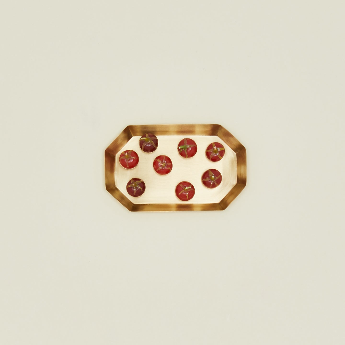 Red tomato candles on a brass tray on a beige background