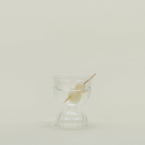 Drinking glass with clear stem and pink cup, filled with a martini.