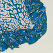 A close up of a ruffled floral cushion with an evergreen pattern.