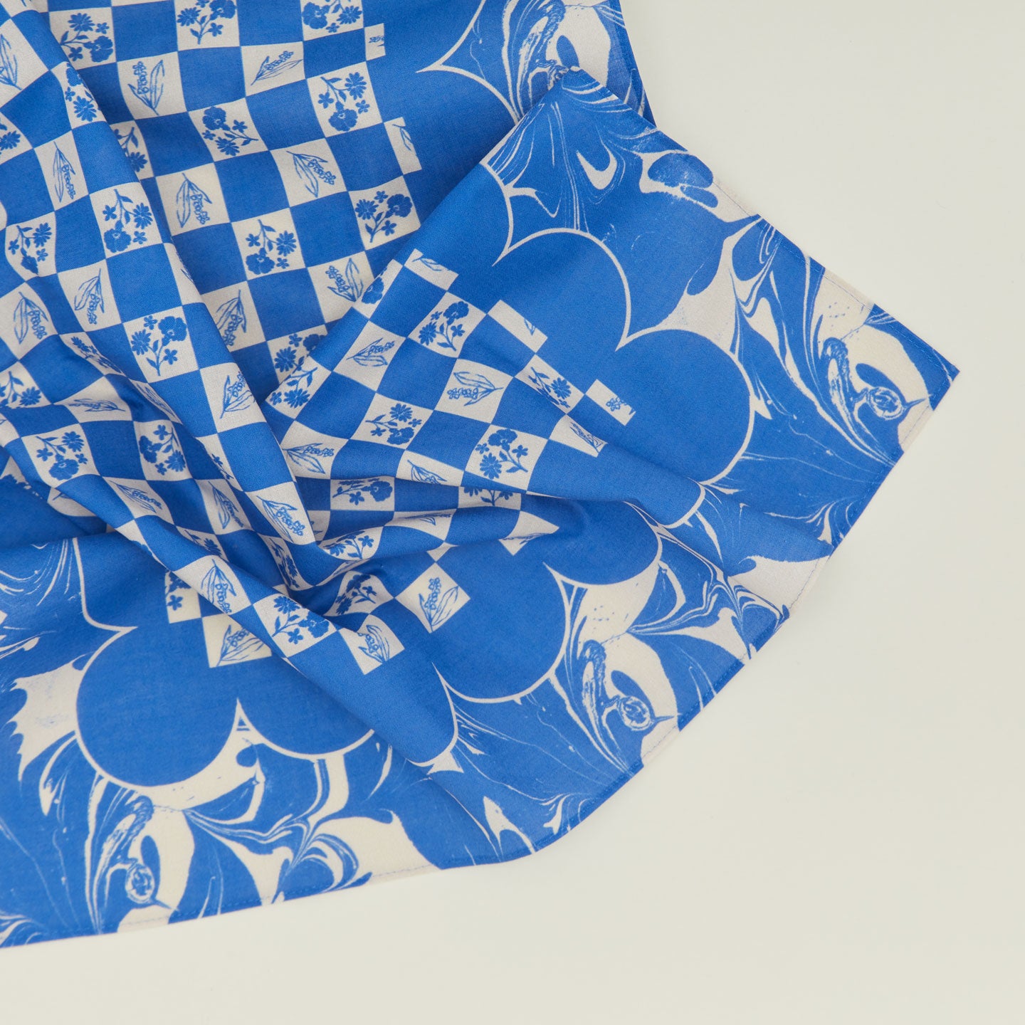 A close up of a mixed floral napkin with a klein blue pattern.