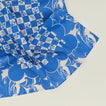 A close up of a mixed floral napkin with a klein blue pattern.