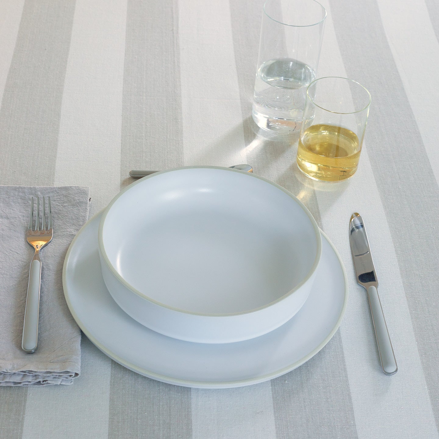 Placesetting with Modernist Low Bowl on ivory striped tablecloth.