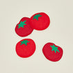 Four red tomato cocktail napkins on a beige background