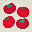 Close up of four red tomato-shaped coasters with green stems on a beige background