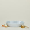 Large porcelain deep oval baker in white with measuring cup and onion 